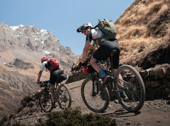 bikepackers descending a mountain with a backpack